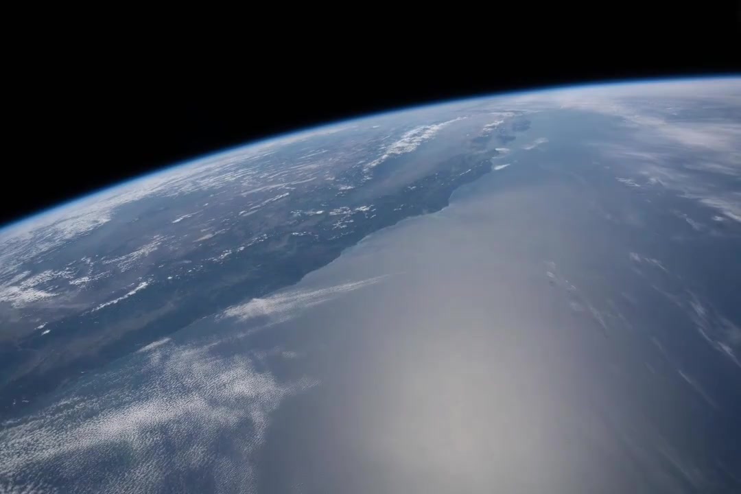 Earth’s curved atmospheric horizon above the Pacific Ocean, western coastline and moving cloud cover