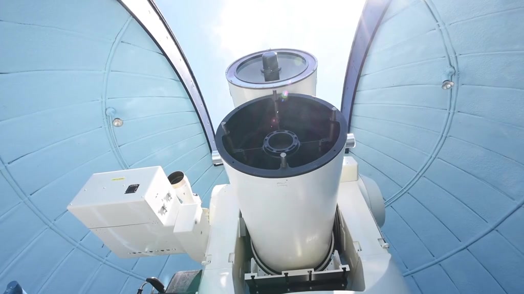 An optical tracking telescope rotating and tilting within its observatory enclosure